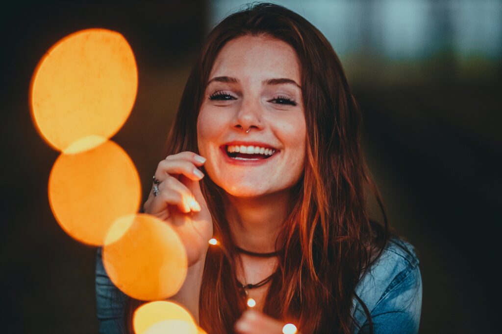 Femme souriante tenant une guirlande lumineuse