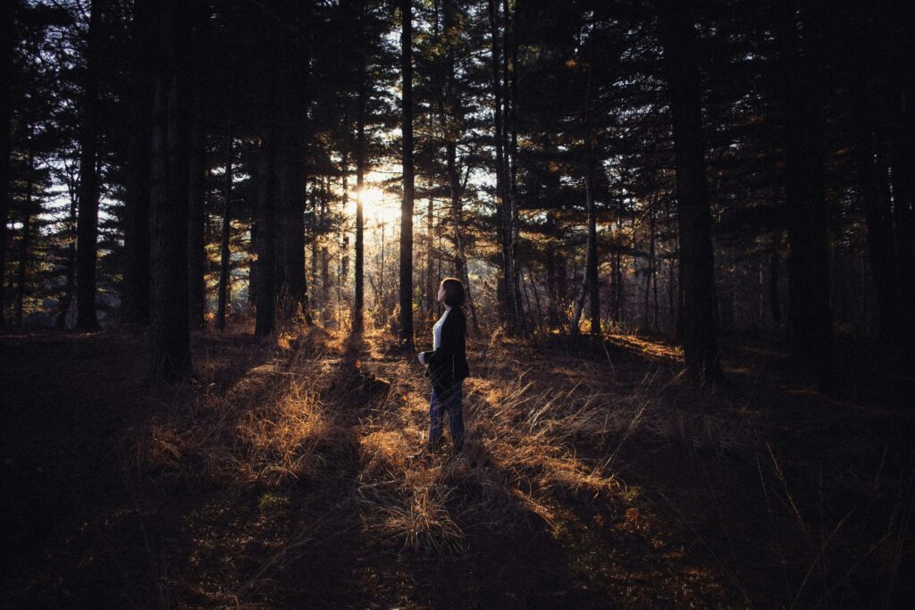 Femme méditant au lever du soleil dans la nature, rechargeant son énergie et retrouvant la sérénité.