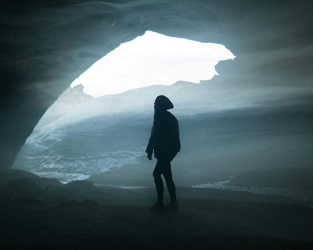 Femme de dos dans le brouillard, à la sortie d'une grotte, symbolisant la clarté et la prise de décision après une période de confusion