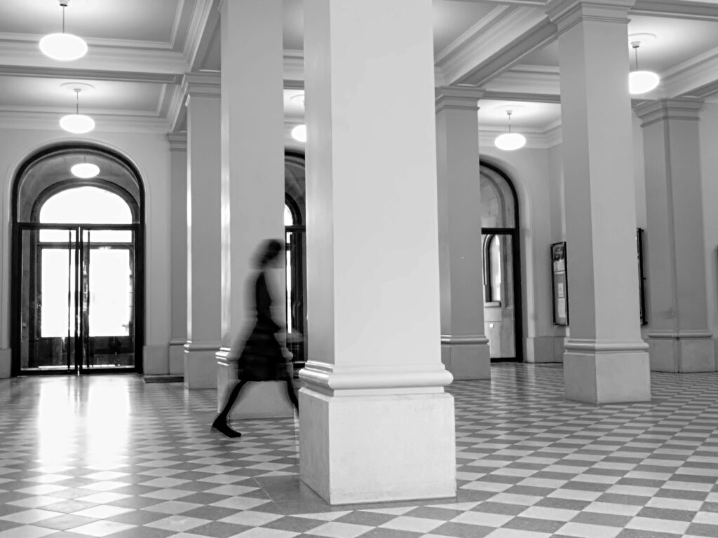 Femme en mouvement dans un grand couloir, flou cinétique noir et blanc — reprendre sa vie professionnelle en main
